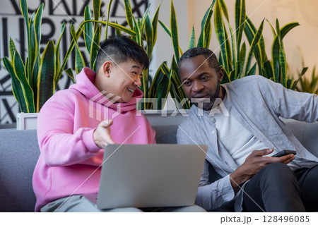 Smiling diverse team members working together on computer in casual office environment 128496085