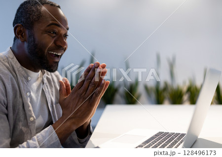 African American man participating in video call on laptop at office desk African American man participating in video call on laptop at office desk 128496173
