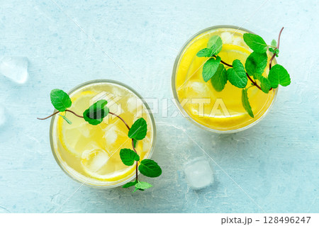 Glasses of lemonade, a mocktail with lemon juice, on a blue background Glasses of lemonade, a mocktail with lemon juice, on a blue background 128496247