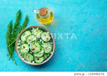 Cucumber salad with olive oil, dill, red onion, and Feta cheese, on blue 128496258