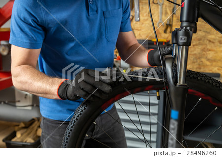 Professional man fixing bike carefully in garage Professional man fixing bike carefully in garage 128496260