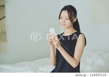 ベッドでスマホを使う女性 128497229