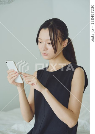 ベッドでスマホを使う女性 128497230
