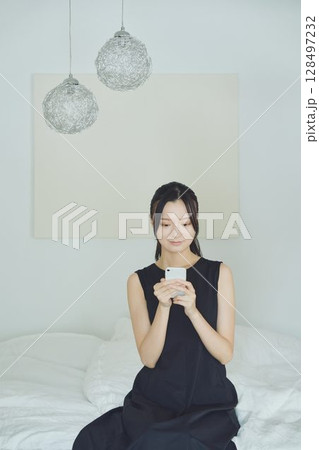 ベッドでスマホを使う女性 128497232