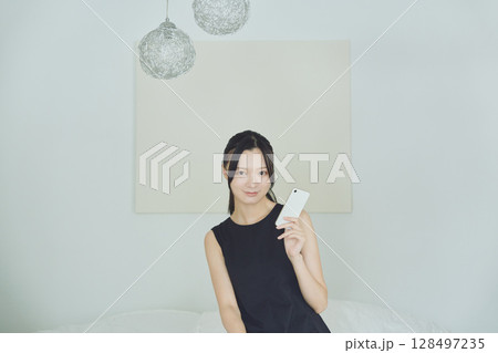 ベッドでスマホを使う女性 128497235