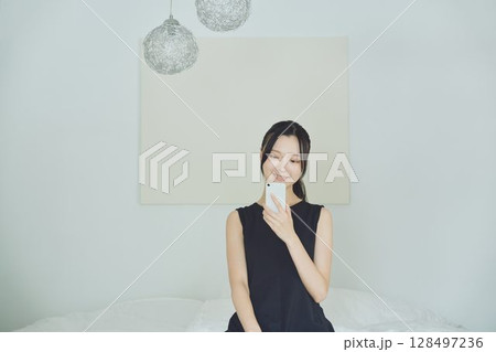 ベッドでスマホを使う女性 128497236