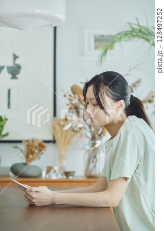 ダイニングでスマホを使う女性 128497252