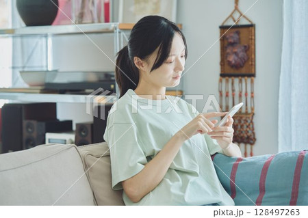 ソファーでスマホを使う女性 ソファーでスマホを使う女性 128497263