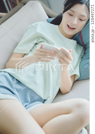 ソファ寝転びながらスマホを使う女性 ソファ寝転びながらスマホを使う女性 128497271
