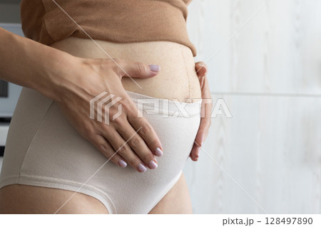 Pregnant woman touching gently her belly. Closeup. 128497890