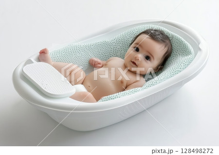 Newborn baby relaxing in a safe plastic bathtub with soft support on a white background 128498272