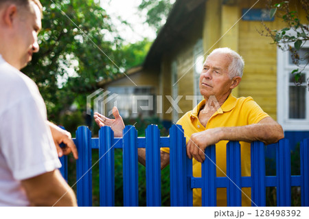 Farm neighbors talk at the border of garden plot 128498392
