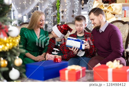 Smiling family celebrating Christmas and giving each other gifts 128498412