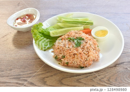 spicy fried rice with mashed salmon topping half boiled egg eat couple fresh vegetable on plate dressing slice chili and garlic fish sauce spicy fried rice with mashed salmon topping half boiled egg eat couple fresh vegetable on plate dressing slice chili and garlic fish sauce 128498980