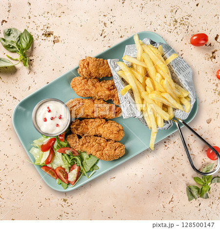 Breaded chicken strips served with french fries 128500147