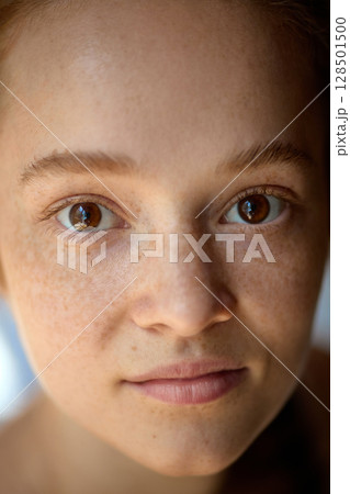 Close-up of calm young woman with freckles and soft natural skin under daylight 128501500