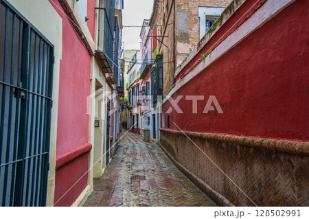 Narrow Alley in Sevilla Spain with Colorful Buildings and Cobblestone Path. Narrow Alley in Sevilla Spain with Colorful Buildings and Cobblestone Path. 128502991