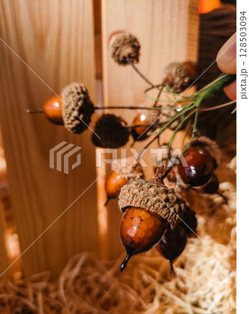 Florist creating autumn decoration with acorns and raffia Florist creating autumn decoration with acorns and raffia 128503094