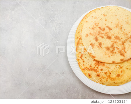 Socca, a typical chickpea flatbread from liguria, resting on a white plate, copy space Socca, a typical chickpea flatbread from liguria, resting on a white plate, copy space 128503134