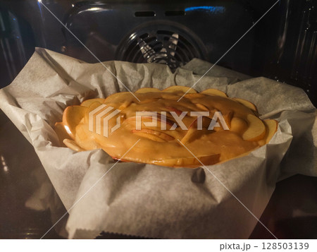 Apple pie baking in the oven on baking paper 128503139