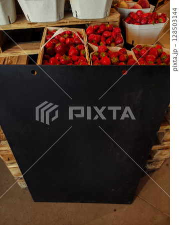 Fresh strawberries displayed at a market with black board 128503144