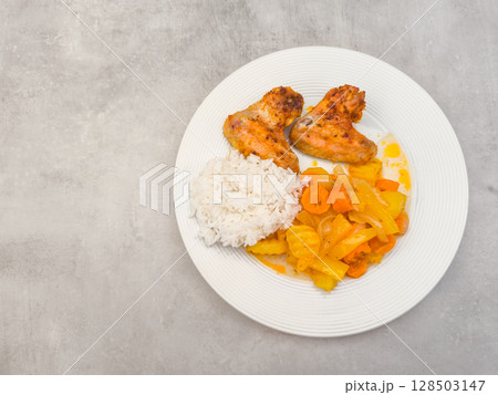 Roasted chicken wings with rice and stewed vegetables on white plate, copy space Roasted chicken wings with rice and stewed vegetables on white plate, copy space 128503147