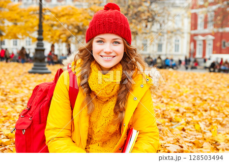Smiling teenage girl with books in autumn park 128503494