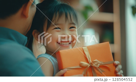 Happy Little Girl Receiving a Gift from Her Father 128504552
