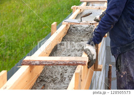 Worker levels concrete in formwork using a trowel Worker levels concrete in formwork using a trowel 128505573