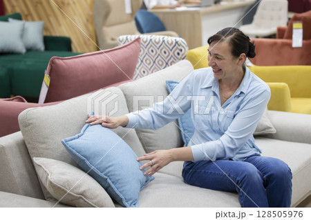A woman chooses a sofa in a furniture store. The client buys furniture. A woman chooses a sofa in a furniture store. The client buys furniture. 128505976