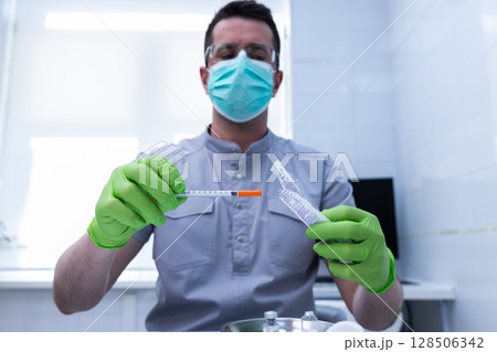 Health Professional Preparing Medical Syringe with Vial in a Sterile Environment, Highlighting Safety Protocols and Hygiene Practices in Modern Healthcare Settings 128506342