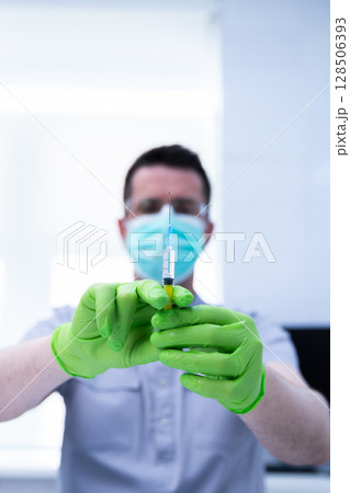Healthcare Professional Prepared for Vaccination with Syringe and Green Gloves in a Modern Medical Setting Focused on Patient Care and Health Promotion Healthcare Professional Prepared for Vaccination with Syringe and Green Gloves in a Modern Medical Setting Focused on Patient Care and Health Promotion 128506393