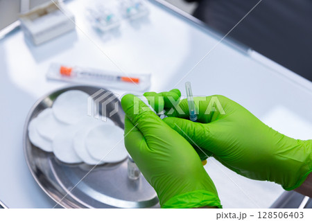 Preparation of Medical Supplies with Sterile Gloves for Health Procedures Close-Up of Hands Ready to Administer Injection Using Proper Techniques and Equipment 128506403
