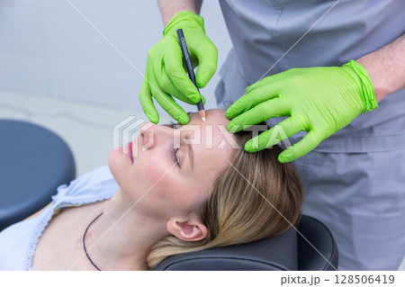 A Skilled Practitioner Preparing for a Safe and Effective Facial Treatment on a Relaxed Patient with Careful Precision in a Modern Medical Setting A Skilled Practitioner Preparing for a Safe and Effective Facial Treatment on a Relaxed Patient with Careful Precision in a Modern Medical Setting 128506419