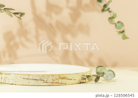 Wooden empty podium for presentation or advertising. Round product display on pink background with eucalyptus leaves and shadows. Concept of scene stage for natural products or promotion sale. Closeup 128506545