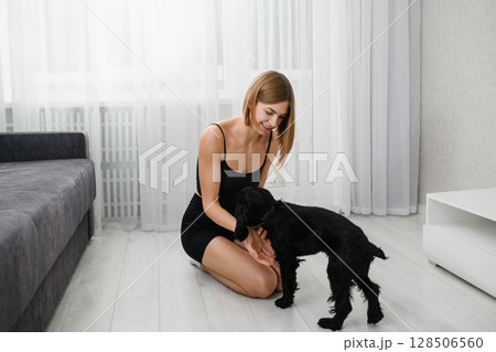 Young woman training black English Cocker Spaniel puppy at home. Young woman training black English Cocker Spaniel puppy at home. 128506560