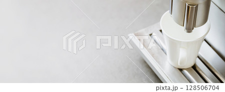 Close-up of white coffee cup on coffee machine on grey marble background. Natural light. Professional coffee brewing. Coffee break. Good morning Close-up of white coffee cup on coffee machine on grey marble background. Natural light. Professional coffee brewing. Coffee break. Good morning 128506704
