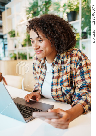 A young woman is seen working diligently on her laptop in a modern and stylish workspace A young woman is seen working diligently on her laptop in a modern and stylish workspace 128506977