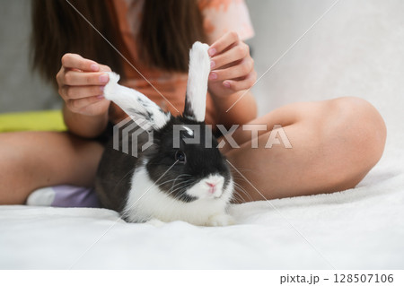 Girl playing with rabbit ears while sitting on bed. Girl playing with rabbit ears while sitting on bed. 128507106