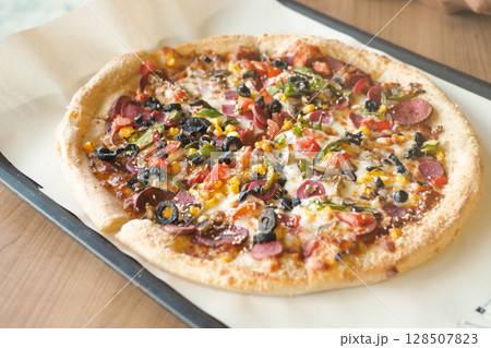 A Delicious Loaded Pizza with an Array of Toppings on a Wooden Table A Delicious Loaded Pizza with an Array of Toppings on a Wooden Table 128507823