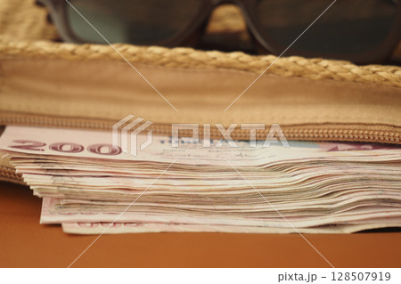 Currency and sunglasses placed inside a woven bag 128507919
