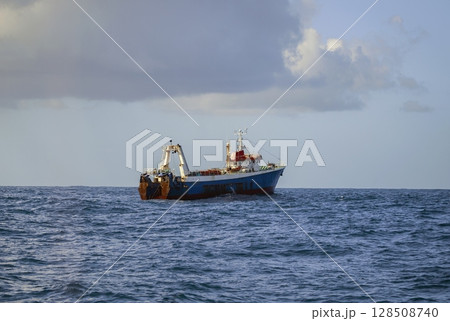 Fishing vessel is conducting an industrial catch of wild marine products using deep-sea trawl. 128508740