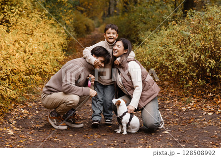 Happy family of three with dog in autumn park Happy family of three with dog in autumn park 128508992