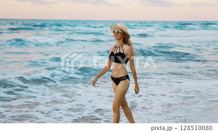 Summer vacation, happy slim woman walking running on sea beach, coast with waves 128510080
