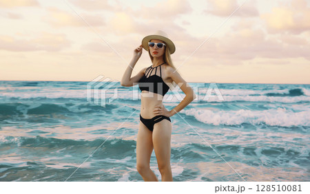 Summer vacation, beautiful young woman in swimsuit, hat standing on sea beach background Summer vacation, beautiful young woman in swimsuit, hat standing on sea beach background 128510081