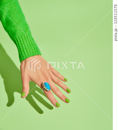 Beautiful womans hands with spring autumn nail design on green background. Manicure, pedicure beauty salon concept Beautiful womans hands with spring autumn nail design on green background. Manicure, pedicure beauty salon concept 128511578
