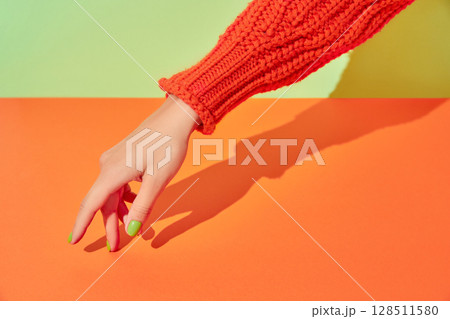 Beautiful womans hand with spring autumn nail design on green and orange background. Manicure, pedicure beauty salon concept Beautiful womans hand with spring autumn nail design on green and orange background. Manicure, pedicure beauty salon concept 128511580