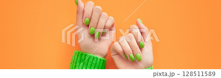 Beautiful womans hands with spring autumn nail design on orange background. Manicure, pedicure beauty salon concept. 128511589