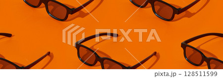 Pattern made with black plastic 3d glasses on orange background Pattern made with black plastic 3d glasses on orange background 128511599