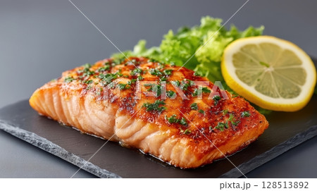Grilled Salmon Fillet Seasoned with Herbs and Lemon on a Slate Plate with Fresh Greens 128513892